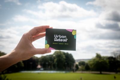 Urban ReLeaf Postcard against the backdrop of a Dundee Greenspace